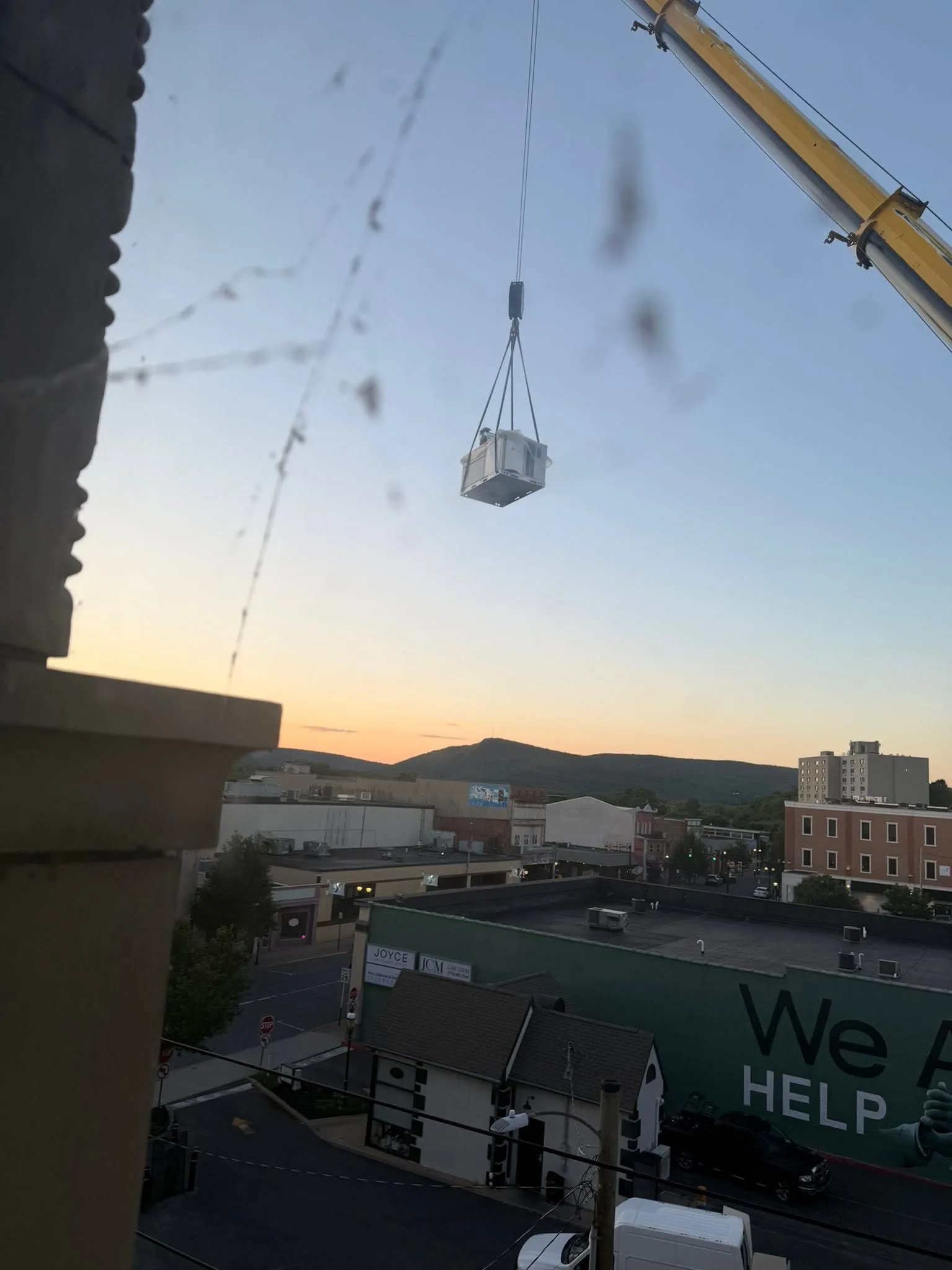 Air conditioning unit being lifted to a rooftop by crane