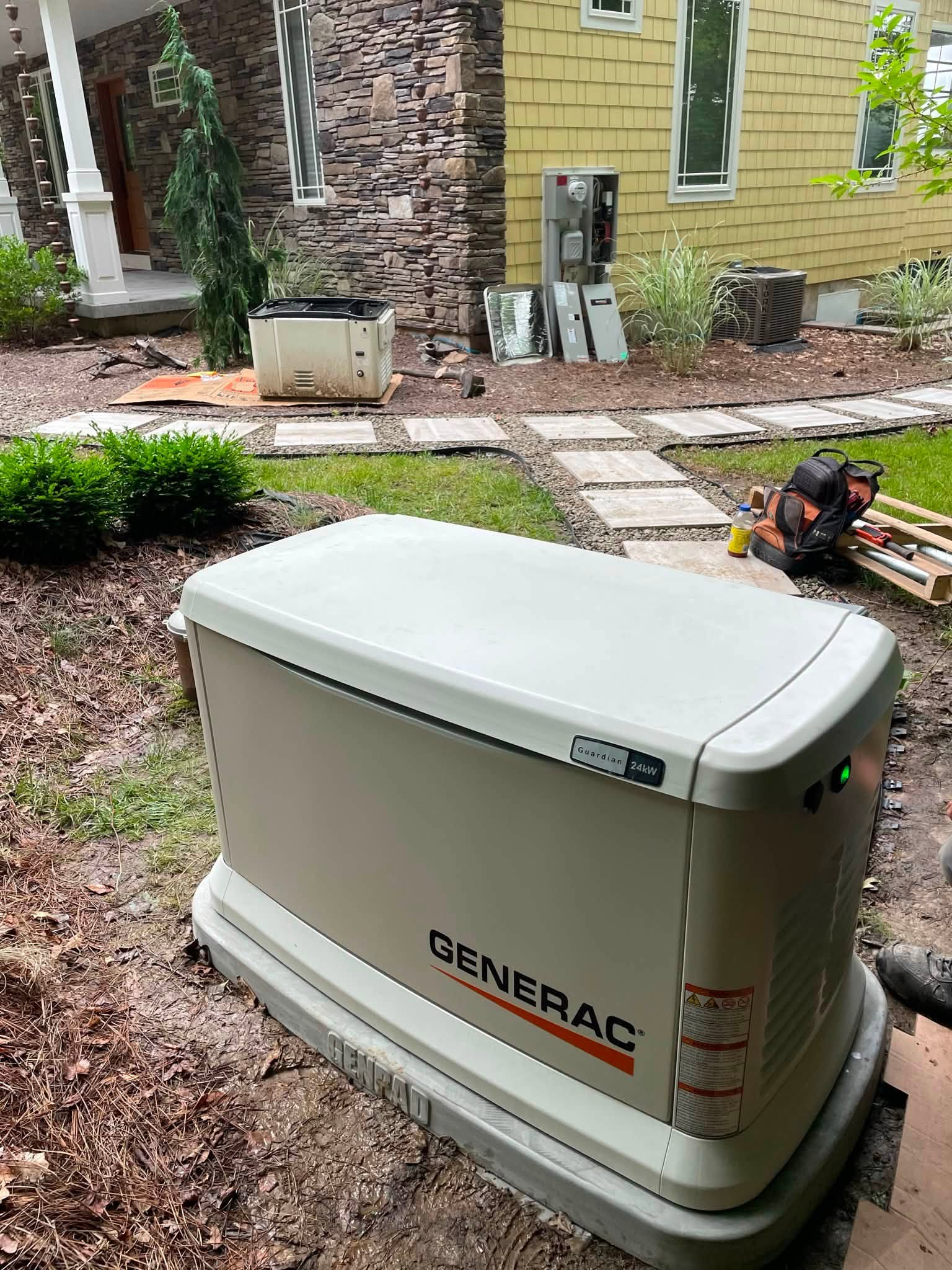 Front and side view of a Generac Guardian standby generator beside a home