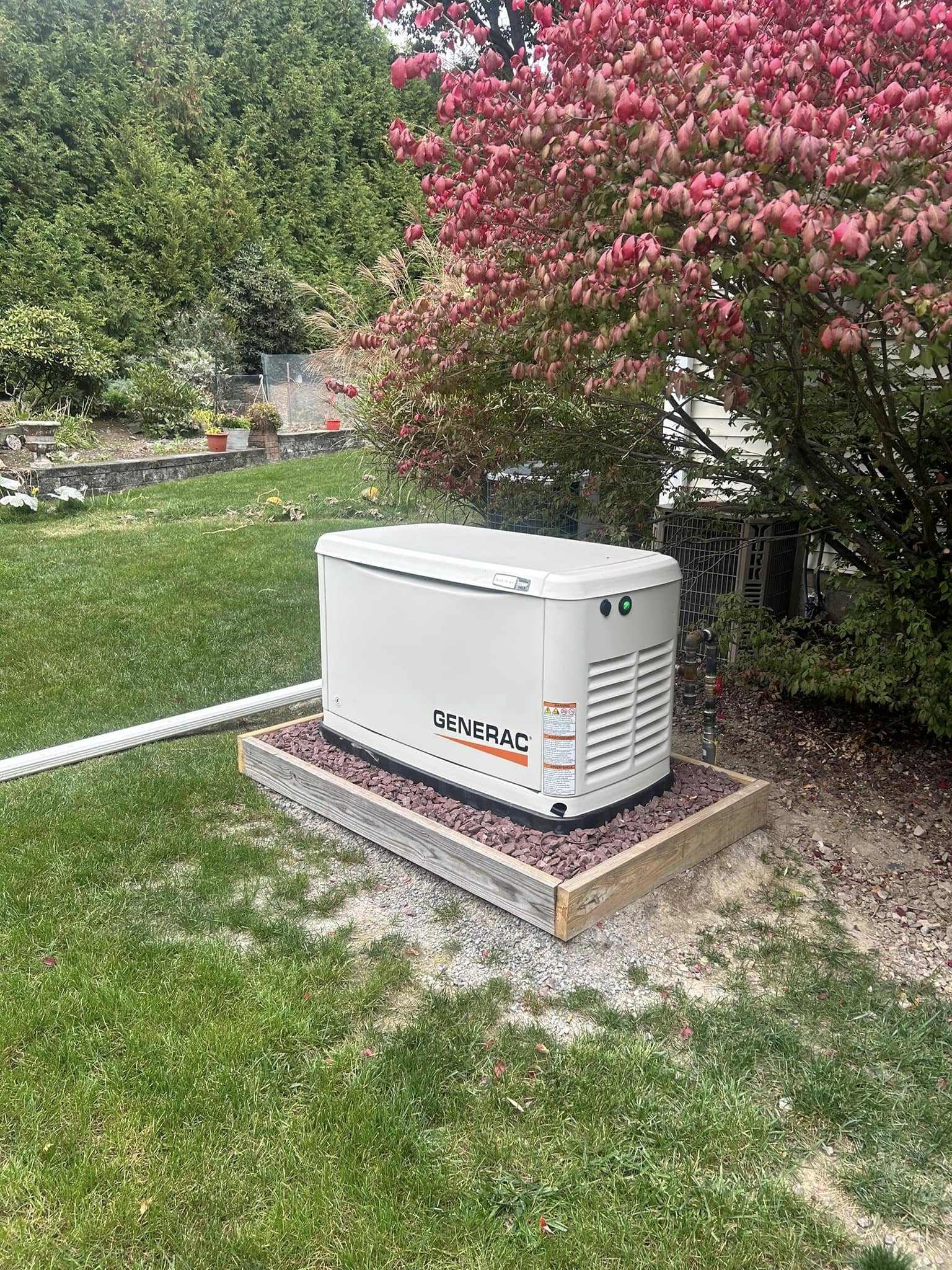 Side view of a Generac Guardian standby generator near landscaping