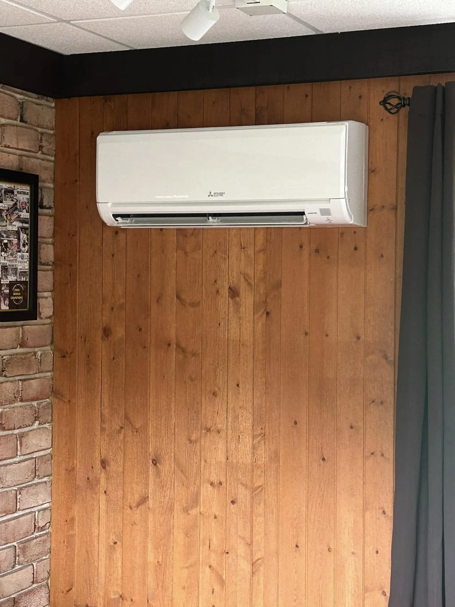 Finished Mitsubishi indoor mini-split unit installation on a wood-paneled wall