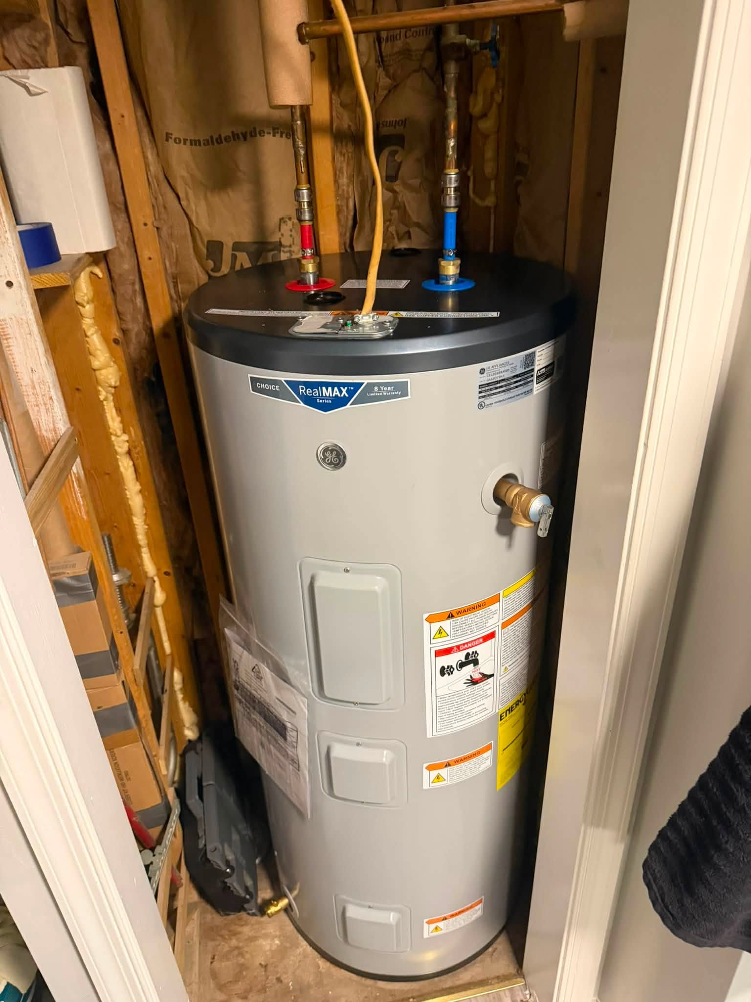 GE water heater with connected piping in a utility space